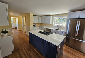 Custom large kitchen with white cupboards, gril in island, large refrigerator.